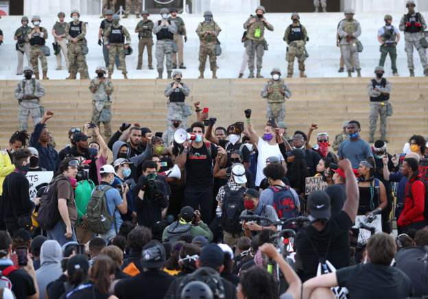 A-man-shouts-from-a-bullhorn-as-curfew-begins-to-take-effect